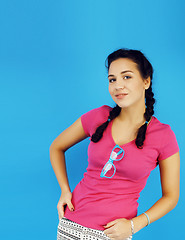 Image showing young pretty teenage modern hipster girl posing emotional happy smiling on blue background, lifestyle people concept 