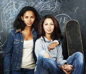 Image showing back to school after summer vacations, two teen real girls in classroom with blackboard painted together, lifestyle mixed races people concept 