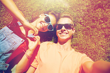 Image showing happy teenage couple taking selfie on summer grass