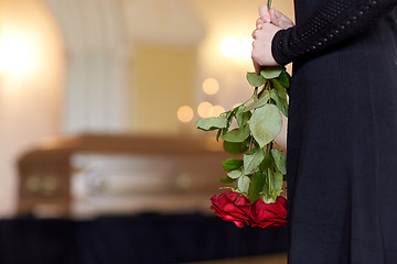 Image showing close up of woman with roses and coffin at funeral