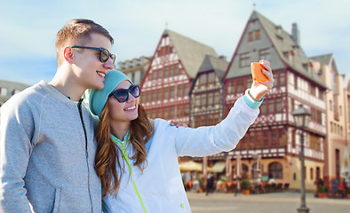 Image showing smiling couple with smartphone taking selfie