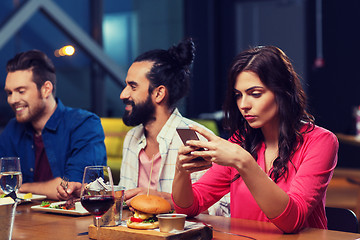 Image showing woman with smartphone and friends at restaurant