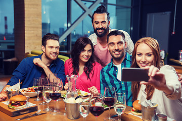 Image showing friends taking selfie by smartphone at restaurant