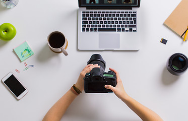 Image showing woman hands with camera working on laptop at table