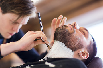 Image showing man and barber with straight razor shaving beard
