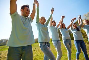 Image showing group of happy volunteers holding hands outdoors