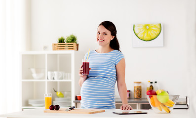 Image showing happy pregnant woman drinking juice at home