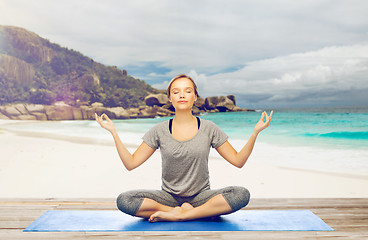 Image showing woman doing yoga meditation in lotus pose on beach