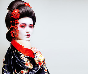 Image showing young pretty geisha in kimono with sakura and red decoration des