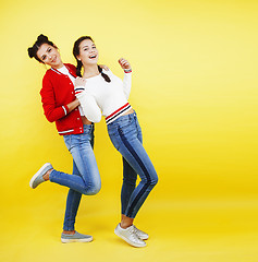 Image showing lifestyle people concept: two pretty young school teenage girls having fun happy smiling on yellow background 