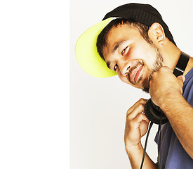 Image showing young asian man in hat and headphones listening music on white b