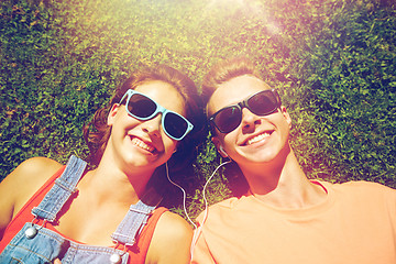 Image showing happy teenage couple with earphones lying on grass