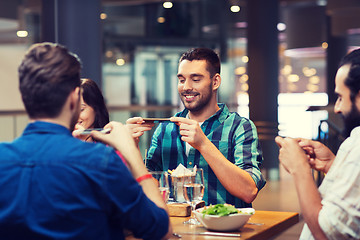 Image showing happy friends taking picture of food at restaurant