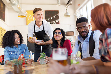 Image showing waiter and friends with menu and drinks at bar