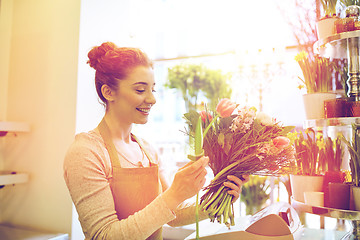 Image showing smiling florist woman making bunch at flower shop