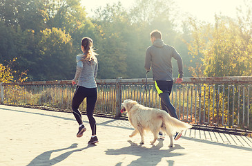 Image showing close up of couple with dog running outdoors