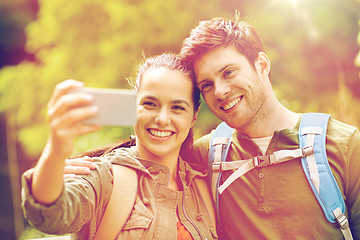 Image showing couple with backpacks taking selfie by smartphone