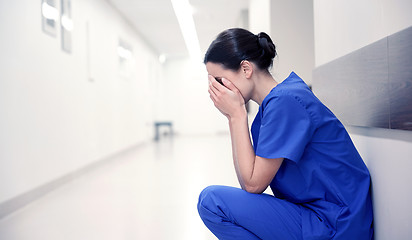 Image showing sad or crying female nurse at hospital corridor