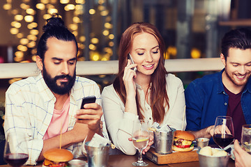 Image showing happy friends with smartphones at restaurant