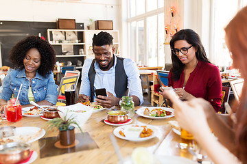 Image showing happy friends with smartphones at restaurant