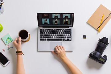 Image showing woman hands with camera working on laptop at table