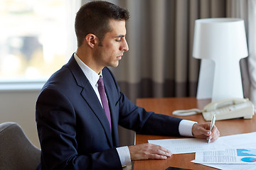 Image showing businessman with papers working at hotel room