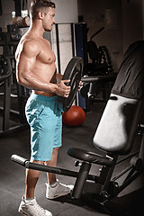 Image showing Muscular bodybuilder guy doing exercises with weight in gym