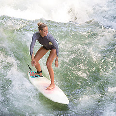 Image showing Atractive sporty girl surfing on famous artificial river wave in Englischer garten, Munich, Germany.