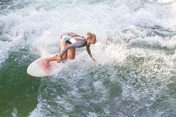 Image showing Atractive sporty girl surfing on famous artificial river wave in Englischer garten, Munich, Germany.