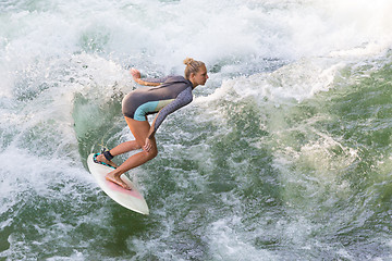 Image showing Atractive sporty girl surfing on famous artificial river wave in Englischer garten, Munich, Germany.