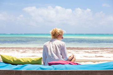 Image showing Relaxed woman in luxury lounger, arms rised, enjoying summer vacations on beautiful beach.