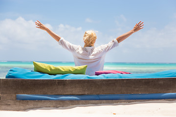 Image showing Relaxed woman in luxury lounger, arms rised, enjoying summer vacations on beautiful beach.