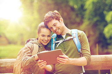 Image showing happy couple with backpacks and tablet pc outdoors