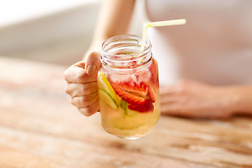 Image showing close up of woman holding glass with fruit water