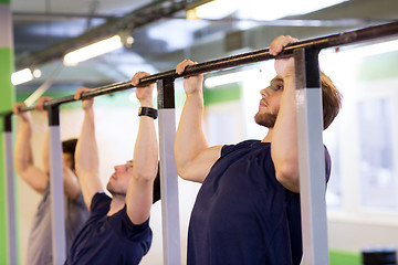 Image showing group of young men doing pull-ups in gym