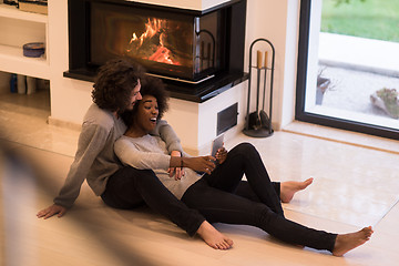 Image showing multiethnic couple using tablet computer on the floor