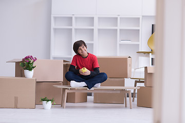 Image showing boy sitting on the table with cardboard boxes around him