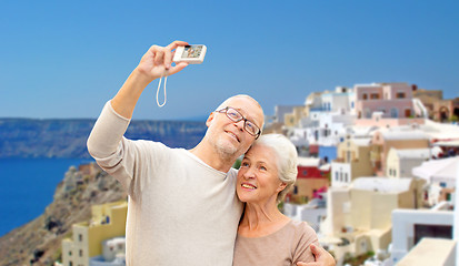 Image showing senior couple with camera travelling in santorini