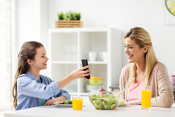 Image showing happy family with smartphone having dinner at home