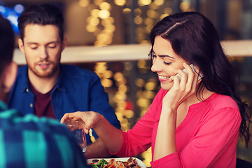 Image showing woman with smartphone and friends at restaurant