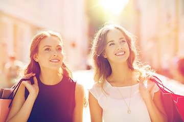 Image showing happy women with shopping bags walking in city 