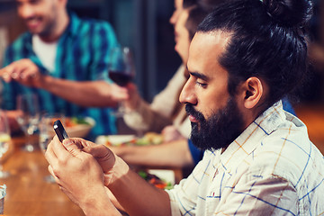 Image showing man with smartphone and friends at restaurant