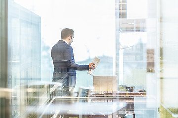 Image showing Businessman talking on a mobile phone while looking through window.