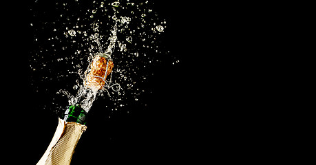 Image showing Champagne cork popping and splashing on black background