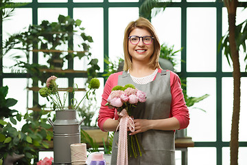 Image showing Young smiling florist in greenhouse