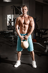 Image showing Muscular bodybuilder guy doing exercises with weight in gym