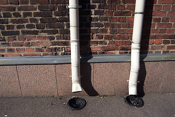 Image showing two old drainpipes on a brick wall