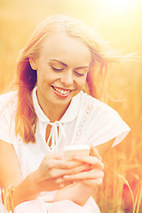 Image showing happy young woman with smartphone on cereal field