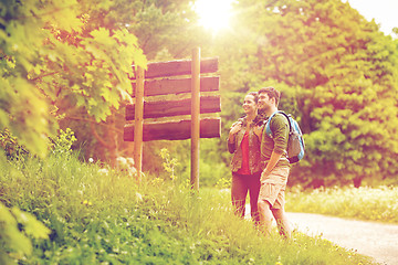 Image showing smiling couple at signpost with backpacks hiking