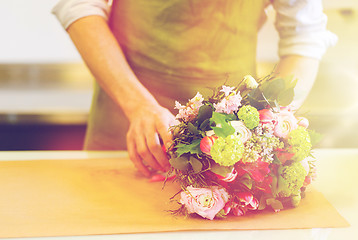 Image showing florist wrapping flowers in paper at flower shop